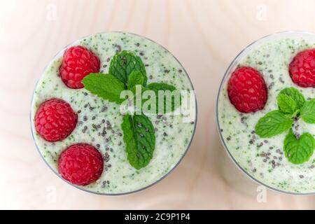 Sellerie Banane Smoothie mit Minze und frischen Himbeeren in Gläsern aus der Nähe auf Holzhintergrund, Blick von oben Stockfoto