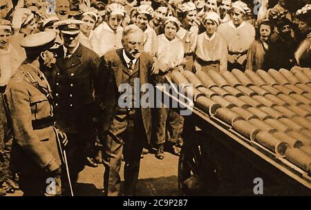 Der erste Weltkrieg - der König (George V) besucht im Januar 1917 eine britische Munitionsfabrik. Während Arbeiterinnen ihn beobachten, wie er einen Wagen voller Muscheln untersucht. Stockfoto