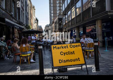 Die Leute sitzen draußen auf der Berwick Street und genießen die Café-Kultur an einem warmen Sommernachmittag, Post Coronavirus Lockdown, Soho, London, England, Großbritannien Stockfoto