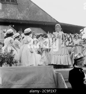 1950er Jahre, historisch, auf einer Plattform vor einem hölzernen Sportpavillon in Farnworth, Lancashire, der neu gekrönten "Rosenkönigin" der Stadt, eine Rede zu halten. In einem Seidenkleid und mit einer Tiara wird das Mädchen die traditionelle Prozession oder Parade führen, die als "Walking Day" bekannt ist, Feiern, die in dieser Zeit im Nordwesten Englands, Großbritannien, üblich waren. Ein jährliches Ereignis, einige stammen aus den 1830er Jahren, wo sie Kirchenparaden waren und viele werden noch heute abgehalten. Stockfoto