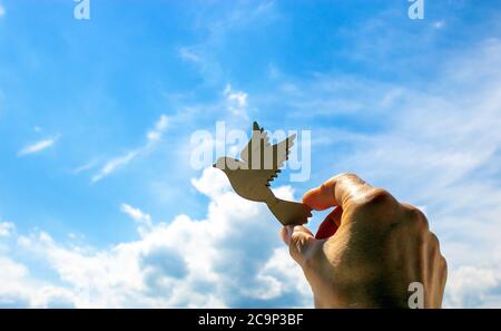 Mann Hand hält hölzernen Vogel auf Wolke Himmel Hintergrund. Die Entwicklung der Phantasie, kopieren Raum. Stockfoto