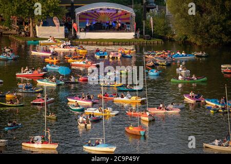 01. August 2020, Bayern, Nürnberg: Die Staatsphilharmonie (h, M) spielt auf der Seestufe auf dem Großen Dutzendteich ein Konzert vor Zuschauern, die das Konzert auf eigenen Booten verfolgen. Aufgrund der musikalischen Veranstaltungen Bardentreffen, Klassik Open Air und Stars in Luitpoldhain, die aufgrund von Corona abgesagt wurden, hat das Projektbüro im Kulturbereich der Stadt Nürnberg drei verschiedene Konzerte mit einem Open-Air-Konzertwochenende am Ufer des Dutzendteichs organisiert. Das einzigartige Angebot soll als Brückenhilfe und Experiment in einem dienen. Das Publikum wird ihr o mitbringen müssen Stockfoto