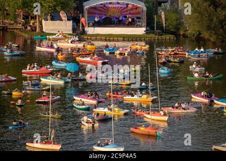 01. August 2020, Bayern, Nürnberg: Die Staatsphilharmonie (h, M) spielt auf der Seestufe auf dem Großen Dutzendteich ein Konzert vor Zuschauern, die das Konzert auf eigenen Booten verfolgen. Aufgrund der musikalischen Veranstaltungen Bardentreffen, Klassik Open Air und Stars in Luitpoldhain, die aufgrund von Corona abgesagt wurden, hat das Projektbüro im Kulturbereich der Stadt Nürnberg drei verschiedene Konzerte mit einem Open-Air-Konzertwochenende am Ufer des Dutzendteichs organisiert. Das einzigartige Angebot soll als Brückenhilfe und Experiment in einem dienen. Das Publikum wird ihr o mitbringen müssen Stockfoto