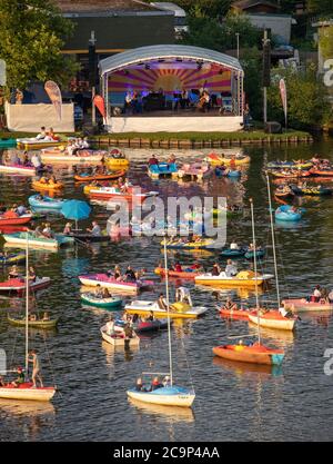 01. August 2020, Bayern, Nürnberg: Die Staatsphilharmonie (h, M) spielt auf der Seestufe auf dem Großen Dutzendteich ein Konzert vor Zuschauern, die das Konzert auf eigenen Booten verfolgen. Aufgrund der musikalischen Veranstaltungen Bardentreffen, Klassik Open Air und Stars in Luitpoldhain, die aufgrund von Corona abgesagt wurden, hat das Projektbüro im Kulturbereich der Stadt Nürnberg drei verschiedene Konzerte mit einem Open-Air-Konzertwochenende am Ufer des Dutzendteichs organisiert. Das einzigartige Angebot soll als Brückenhilfe und Experiment in einem dienen. Das Publikum wird ihr o mitbringen müssen Stockfoto