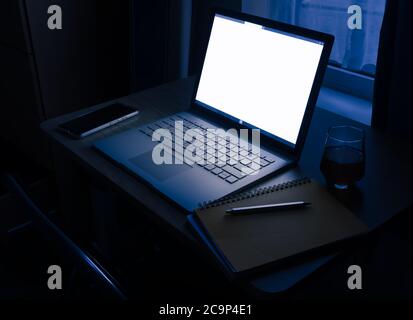 WFH - Überstunden und Arbeit von zu Hause spät in der Nacht auf Laptop mit Glas Whisky 2 Stockfoto