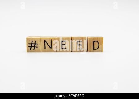 Ein Wort BRAUCHEN mit Hashtag. Kleine Holzwürfel mit Buchstaben isoliert auf weißem Hintergrund mit Kopierplatz zur Verfügung. Konzeptbild mit Hashtag. Stockfoto