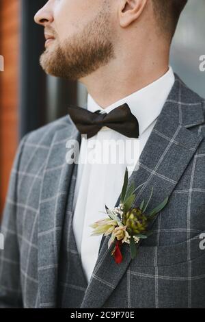 Nahaufnahme eines gut aussehenden Mannes, eines jungen Bräutigams in Fliege und kariertem Anzug mit Boutonniere auf der Tasche Stockfoto
