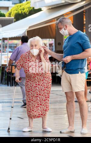Punta Umbria, Huelva, Spanien - 10. Juli 2020: Eine ältere Frau und ein Mann auf der Straße mit Schutzmaske wegen covid-19. Neue Normalität in Spanien Stockfoto