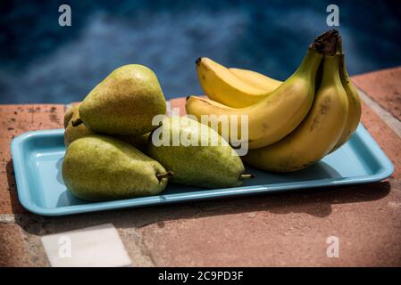 Bananen und Birnen auf blauem Tablett Stockfoto