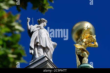 Potsdam, Deutschland. Juli 2020. Der vergoldete Atlas neben einer der Sandstein-Frauenfiguren, die auf dem Dach des Alten Rathauses in der Innenstadt stehen. Die rund 650 Kilogramm schwere Bronzefigur wurde 2008 in der Werkstatt des Berliner Restaurators Georg Ignaszenwski umfassend restauriert und die Oberfläche mit rund 400 Gramm Blattgold bedeckt. Nach der griechischen Mythologie des Zeus, des Vaters der Götter, ist die Figur des Titan Atlas dazu verurteilt, den Himmel auf seinen Schultern für alle Zeit zu tragen. Quelle: Soeren Stache/dpa-Zentralbild/ZB/dpa/Alamy Live News Stockfoto