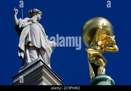 Potsdam, Deutschland. Juli 2020. Der vergoldete Atlas neben einer der Sandstein-Frauenfiguren, die auf dem Dach des Alten Rathauses in der Innenstadt stehen. Die rund 650 Kilogramm schwere Bronzefigur wurde 2008 in der Werkstatt des Berliner Restaurators Georg Ignaszenwski umfassend restauriert und die Oberfläche mit rund 400 Gramm Blattgold bedeckt. Nach der griechischen Mythologie des Zeus, des Vaters der Götter, ist die Figur des Titan Atlas dazu verurteilt, den Himmel auf seinen Schultern für alle Zeit zu tragen. Quelle: Soeren Stache/dpa-Zentralbild/ZB/dpa/Alamy Live News Stockfoto