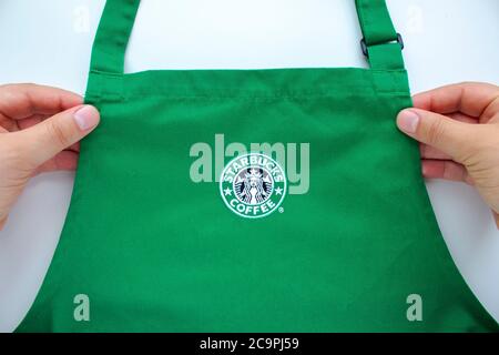 Calgary, Alberta, Kanada. August 2020. Ein Starbucks Mitarbeiter, der eine Schürze mit Markenlogos im Laden hält. Stockfoto