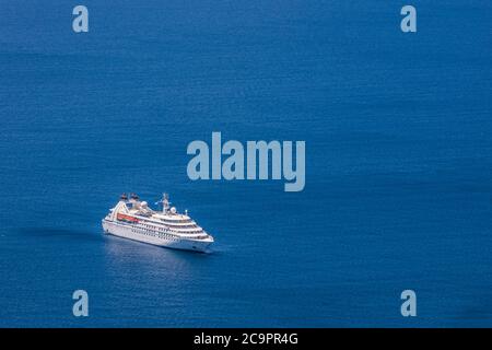 Großes Kreuzfahrtschiff im Meer bei Sonnenuntergang. Wunderschöne Meereslandschaft, tropische Insel Sommerurlaub und Urlaubskonzept. Stockfoto