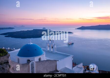 Kirche St. Spirou in Firostefani. Tolle Aussicht am Abend Caldera, Vulkan von Santorini, Griechenland mit Kreuzfahrtschiffen Sonnenuntergang Himmel. Berühmtes Reiseziel Stockfoto