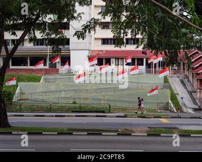 SINGAPUR – 31. JUL 2020 – Menschen gehen an einer Reihe von Singapur Nationalflaggen in Sin Ming HDB Wohngebiet in Vorbereitung auf National Da platziert Stockfoto