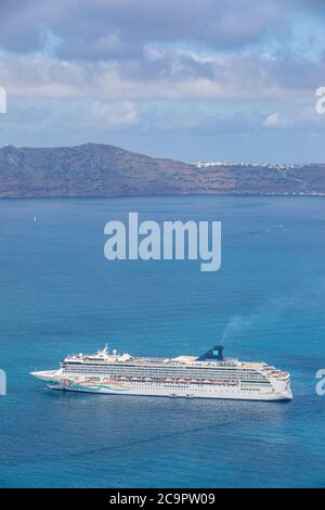 10.05.19. - Santorini, Griechenland: Norwegisches Jade Kreuzfahrtschiff in der Bucht von Santorini, Blaues Wasser mit vulkanischen Klippen am Horizont. Luxuskreuzfahrtschiff Fira Stockfoto