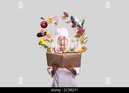 Der Koch schaut sich das Rezept im Kochbuch an Stockfoto