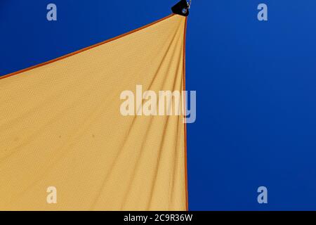 Gelber Stoff, der als Sonnenschutz auf der anderen Straßenseite gestreckt ist Stockfoto