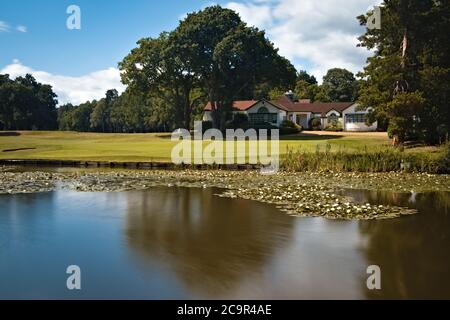 Woking Golf Club House Blick über den seidigen Teich mit Frisch geschnittenes Gras und ein strahlender Sommerhimmel Stockfoto