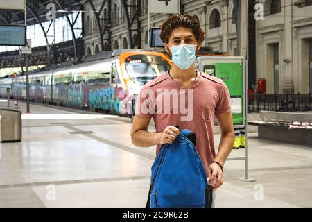 Junger Mann verlässt den Bahnhof mit Gesichtsmaske an. Amerikanisches Flugzeug. Stockfoto