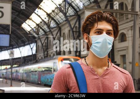 Junger Mann verlässt den Bahnhof mit Gesichtsmaske an. Nahaufnahme. Stockfoto