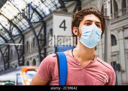 Junger Mann verlässt den Bahnhof mit Gesichtsmaske an. Nahaufnahme. Stockfoto