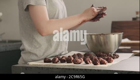 Junge Frau, die Schokoladentrüffel auf heimigeren Kictchen zubereitet Stockfoto