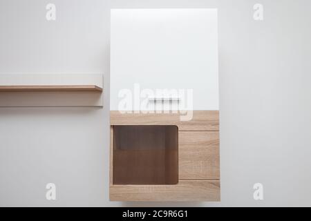 Holzschrank im Wohnzimmer. An der Wand hängendes Sideboard aus weißem Holz Stockfoto