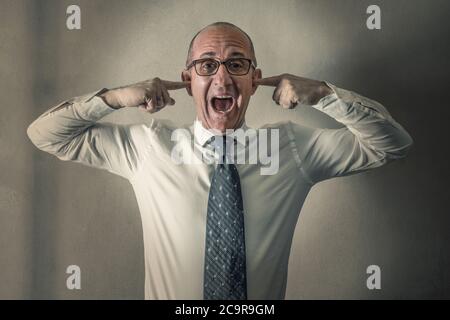 Ein gestresster Manager schreit mit den Fingern in den Ohren Stockfoto