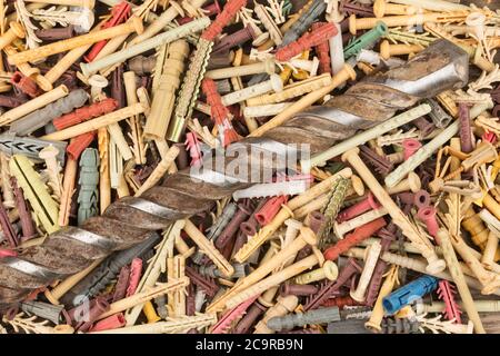 Alte Bohrer zum Bohren von Beton liegt auf einem Haufen Dübeln. Close-up. Ansicht von oben Stockfoto