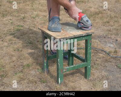 Der Mann Hände arbeiten mit eletrischen Schleifmaschine, Werkzeug zum Schleifen und Polieren der Oberfläche, Renovieren und Polieren alten hölzernen kleinen Tisch Stockfoto