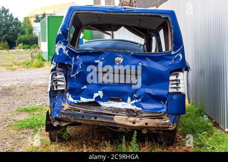 Der Crash-Car Rückansicht, gebrochener Minibus nach Unfall. Gescheiterter blauer Van auf der Landstraße, in der Nähe eines metallgrau Zaun. Stockfoto