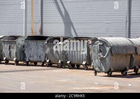 Abfalleimer stehen in einer Reihe in der Nähe einer grauen Metallwand. Stockfoto