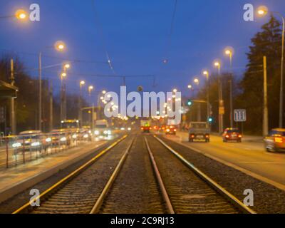 Bunte unscharfe Straßentramway Linie mit Ampeln mit defokussieren Straßenbahn und Autos während des Twiling Stockfoto