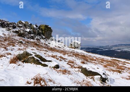Landschaftlich reizvolle ländliche Winterlandschaft (hohe Felsvorsprung, schneebedeckte Hügel, Tal, tiefblauer Himmel) - Cow & Calf Rocks, Ilkley Moor, Yorkshire, England, UK. Stockfoto