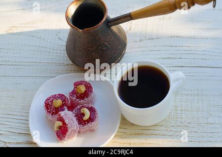 Kaffeebecher, türkischer Genuss mit Nüssen und Kupfer Cezve auf einem hellen Holztisch im Sonnenlicht Stockfoto