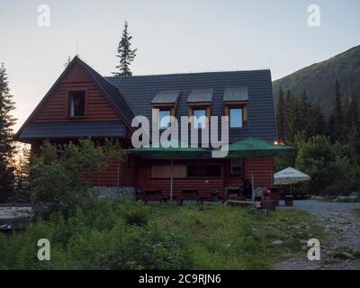 Slowakei, Westtatra, Rohacska dolina, 2. Juli 2019: Frontalansicht der Berghütte Tatliakova Chata, Holzhütte bei Sonnenuntergang Stockfoto