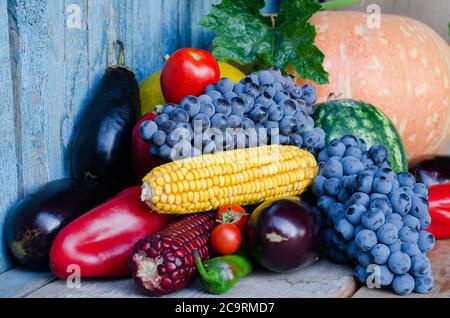 Stillleben von Mais, Trauben, Auberginen, Kürbissen und Paprika auf dem alten Hintergrund. Stockfoto