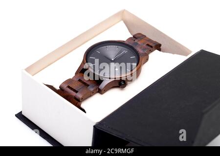 Armbanduhr aus Holz mit einem Armband und einem runden Zifferblatt in einem Karton verpackt, ein Accessoire in einem Paket auf weißem Hintergrund. Stockfoto