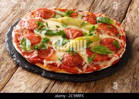 Rustikale Chorizo-Pizza mit Chilischoten, Käse, Tomaten und Kräutern aus der Nähe auf einem Schiefertafel auf dem Tisch. Horizontal Stockfoto