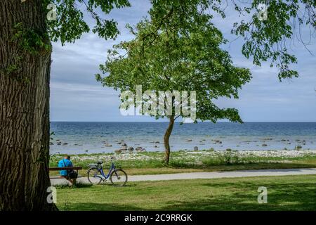 Ein unverkennbarer Mann mit Fahrrad macht eine Pause am Wasser in Visby auf Gotland. Gotland ist die größte schwedische Insel in der Ostsee. Stockfoto