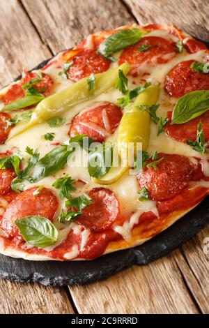 Chorizo Pizza mit scharfer Chili, Mozzarella, Basilikum und Petersilie Nahaufnahme auf einem Brett auf dem Tisch. Vertikal Stockfoto