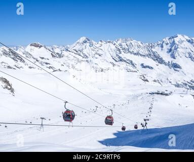 Stubaier Gletscher, ÖSTERREICH, 2. Mai 2019: Schneebedeckte Pisten mit freien Fahrten und Pisten und roten Bergbahnen und Sesselliften auf dem Gipfel der Scha Stockfoto