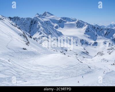 Winterlandschaft mit schneebedeckten Berghängen und Pisten mit Skifahrern genießen Frühling sonnigen Tag im Skigebiet Stubai Gletscher, Stubaital, Tirol, Stockfoto