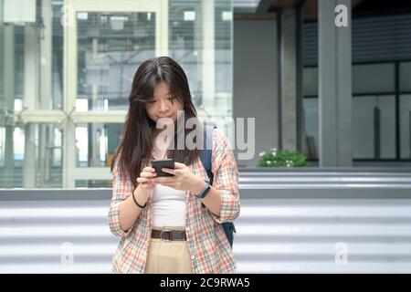 Junge chinesische Mädchen mit ihrem Handy, um Text oder Nachricht. Digitales Lifestyle-Konzept. Stockfoto