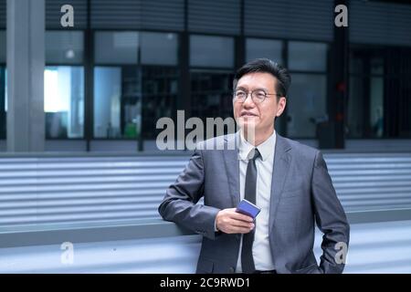 Porträt eines chinesischen Geschäftsmannes in Anzug und Krawatte, lächelnd und aufblickend Stockfoto