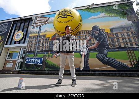 Der Graffiti-Künstler Silent Hobo posiert für ein Foto vor seinem gemalten Wandgemälde auf dem Gelände von Bristol County. Stockfoto