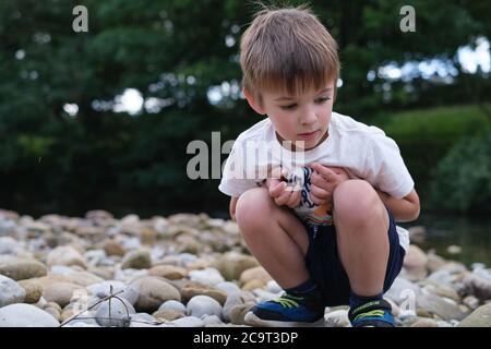 Junge spielt mit Steinen neben Strom Stockfoto