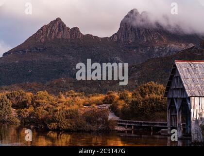 Nahaufnahme der berühmten boatshed mit Cradle Mountain bei Sonnenaufgang am Dove Lake Circuit, Cradle Mountain - Lake St Clair National Park, Tasmanien Stockfoto