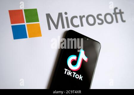 Stone / UK - 2. August 2020: TikTok und Microsoft Deal Konzeptfoto. TikTok App auf dem mobilen Bildschirm und Microsoft-Logo auf dem Papier zu sehen. Hauptfokus Stockfoto